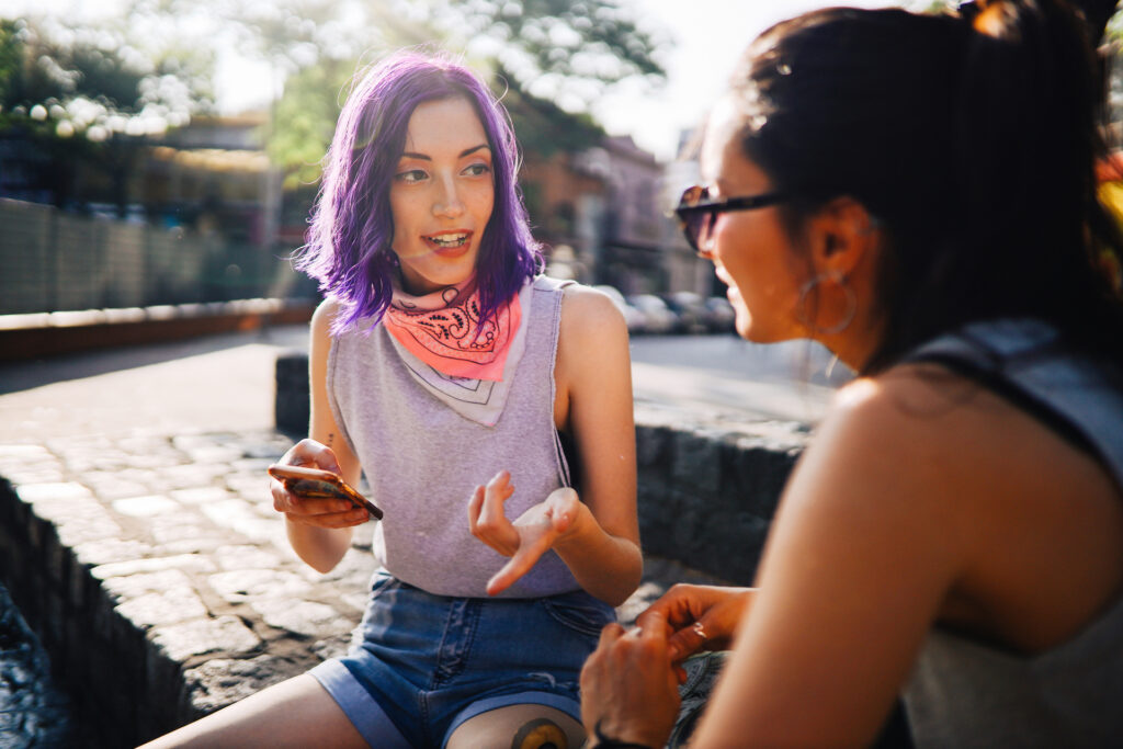 Two young women sitting in the street and talking, Buenos Aires, Argentina.